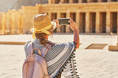 Tourist woman taking photo od ruins Mortuary Temple of Hatshepsut