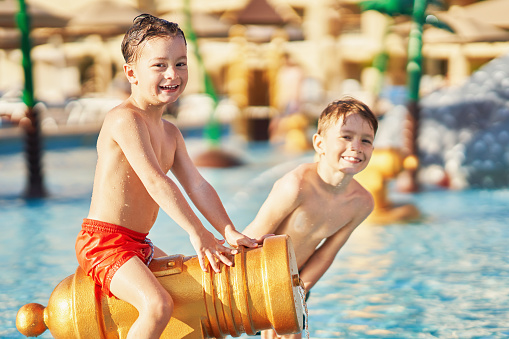 Picture of brothers playing in outdoor aqua park pool. High quality photo