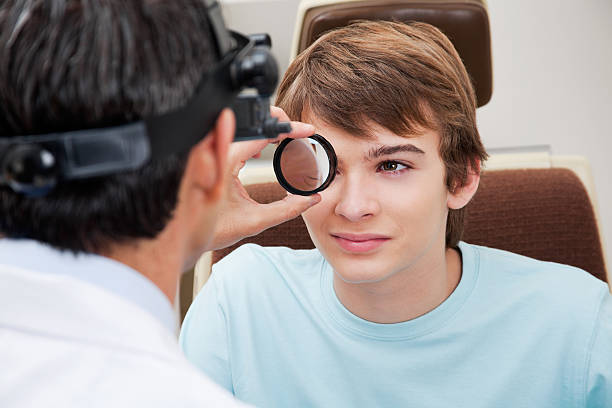 Optometrist performing Dilated Retinal Exam Optometrist taking a closer look at pupil while performing dilated retinal exam dilation stock pictures, royalty-free photos & images
