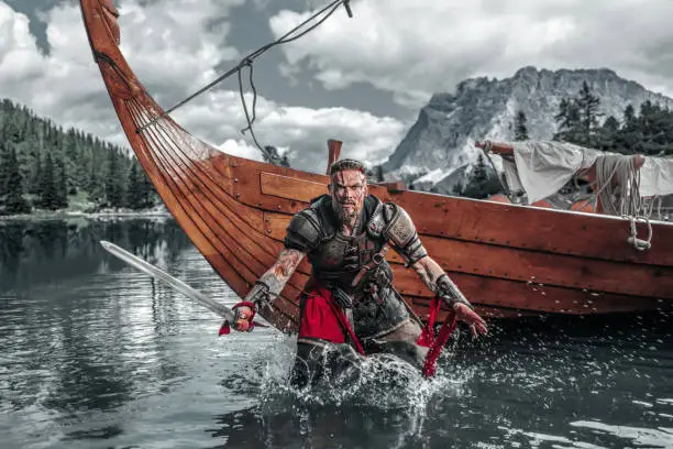 Handsome Viking Warrior sailing on a fjord on an authentic viking long boat
