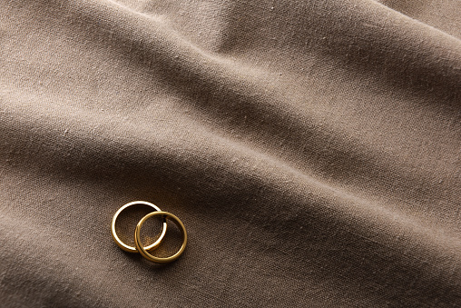 Detail of two elegant gold rings on brown fabric with wrinkles. Top view.