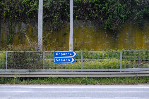 blue road sign for destination name and direction arrow on metal fences. selective Focus Sign. Sapanca and Kocaeli.