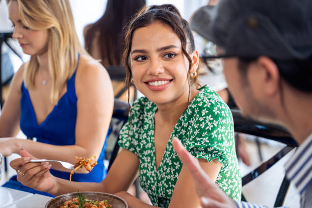 grupo de amigos diversos hablando y comiendo juntos en el restaurante. hombres y mujeres jóvenes atractivos se sienten felices y se relajan, divirtiéndose en el interior disfrutando de la reunión en la cafetería del café. - two party system fotografías e imágenes de stock