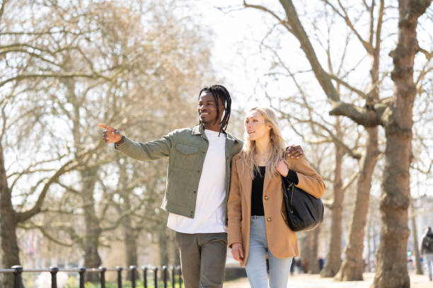 Couple walk down The Mall on sunny spring day in London