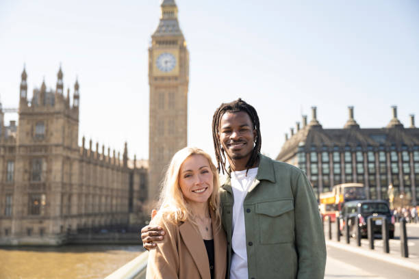 Portrait of multiracial couple in front of Big Ben Smiling, happy posed holiday photo of mid adult black male and young white female on Westminster Bridge in front ion the Houses of Parliament big ben stock pictures, royalty-free photos & images