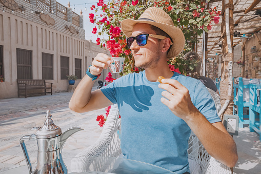 As he sits in a traditional cafe in the UAE, man sips on fragrant Arab coffee and nibbles on sweet dates, immersing himself in the rich culture and history of the region.