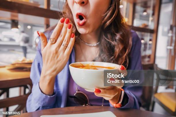 Girl Tries A Spicy And Hot Tom Yam Soup In A Restaurant And Reacts Funny Emotionally Seasonings In The National Cuisine And An Unhealthy Diet With Overabundance Of Pepper Stock Photo - Download Image Now
