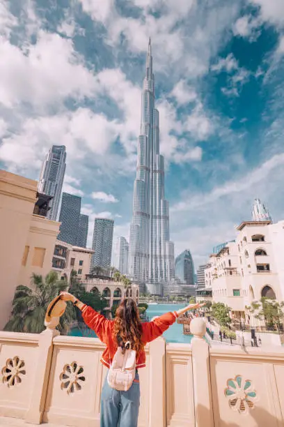 Photo of Happy girl arms are outstretched, as she embracing the incredible view before her with unreal Burj Khalifa tower in Dubai, UAE