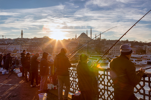 Istanbul, Turkey- Jan 9, 2023: Crowd of local fishermen fishing on Karakoy in Istanbul, Turkey. Galata Bridge, Istanbul bosphorus, fishing rod with the fish hunting