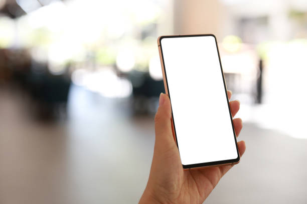 istock A hand holding a mobile smartphone with a blank screen, set against a blurred background of a shopping mall. 1487694680