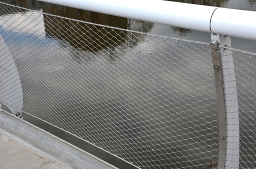 stainless steel mesh stretched on the bridge railing. the lower steel rope serves as a barrier to the water drain. the wheelchair user does not have to crash, the bike is guided by a cable on the side, tensioner, net