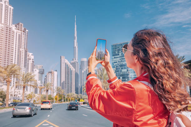 szczęśliwa turystyczna dziewczyna robiąca zdjęcia do swojego bloga podróżniczego, w dzielnicy dubai downtown na tle najwyższego wieżowca burj khalifa - burj zdjęcia i obrazy z banku zdjęć