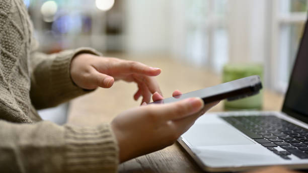 istock A woman using her smartphone while working on her tasks at her desk 1487698137