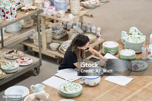 istock Female worker checking orders of ceramic products in ceramics manufacturing factory 1487698489
