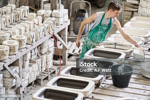 istock Young male worker filling clay into moulds at a ceramic factory 1487698504