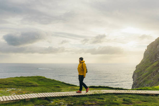 istock Man backpacker hiking on footpath on scenic Runde island with ocean view in Norway 1487698929