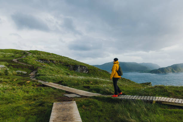 istock Man backpacker hiking on footpath on scenic Runde island with ocean view in Norway 1487700100