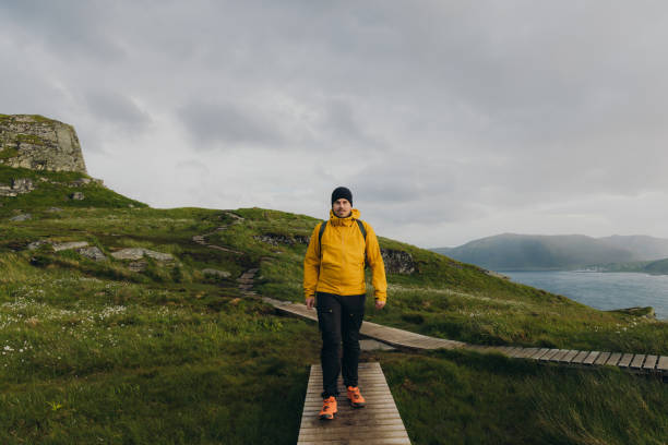 istock Front View of man backpacker hiking on scenic Runde island in Norway 1487700337