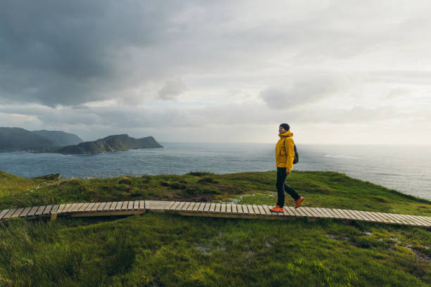 Man backpacker hiking on footpath on scenic Runde island with ocean view in Norway