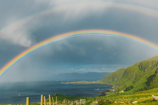 Dramatic sky with bright two rainbows above island of Runde during sunset in Western Norway, Scandinavia