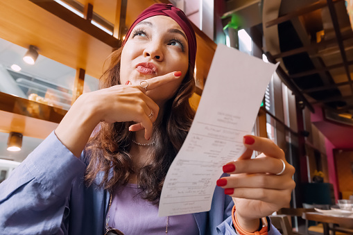 The girl's face was etched with a mix of confusion as she scrutinized the bill in front of her in restaurant. Something didn't add up, and she wasn't sure whether it was a mistake or a hidden charge.