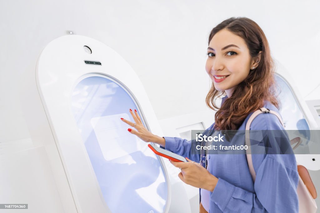 A female customer uses a terminal or self-service kiosk to order at a fast food restaurant or buy tickets to museum or transport Museum Stock Photo