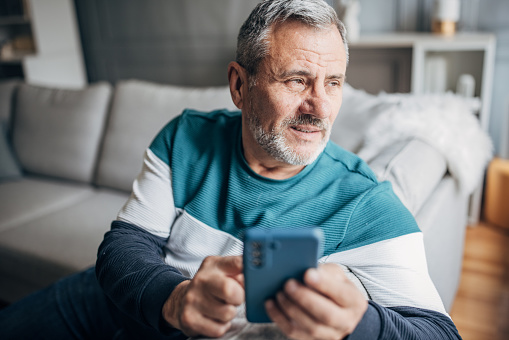 An elderly man uses a mobile phone to chat online