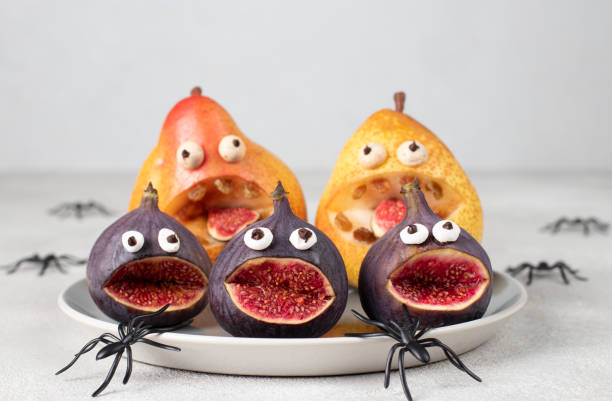 istock Spooky pear and fig monsters for Halloween party on gray background decorated with spiders, Halloween Fruit Serving Idea 1487708906