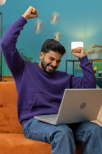 Oh my God Wow. Surprised indian man using laptop computer, receive good news message, shocked by sudden victory, celebrate lottery jackpot win purchases online shopping at home. Lifestyle technologies