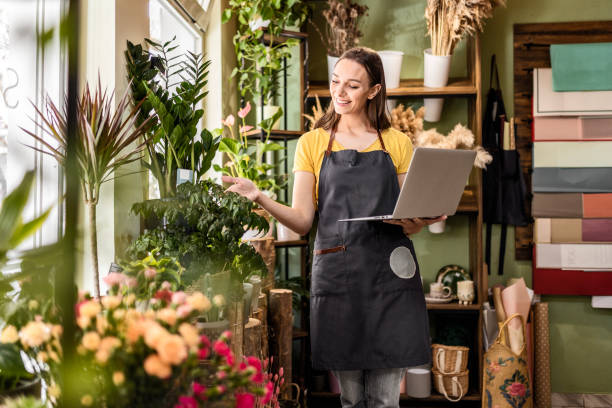 istock Flower vendor is working on the laptop going through checklist 1487711372