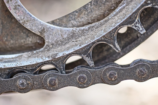 part of a gray metal sprocket with a black iron chain on a bicycle