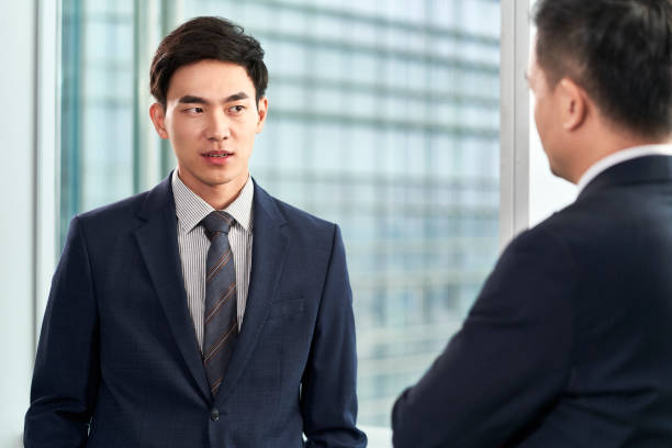 istock two asian businessmen chatting in office 1487712081