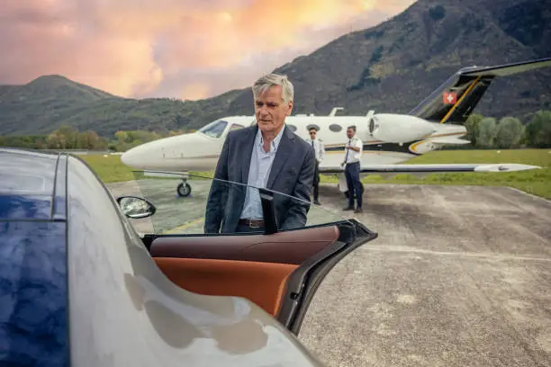 Photo of Chauffeur opening luxury car door, private jet in the background