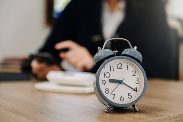 istock Alarm clock on the desk. Business working in modern office building or home at night using laptop. 1487713306