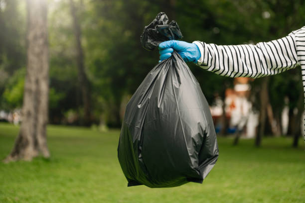 istock Hand holding garbage black bag putting in to trash to clean. Clearing, pollution, and plastic concept. 1487713333
