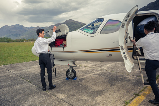 Private jet pilot loads client bag into storage compartment