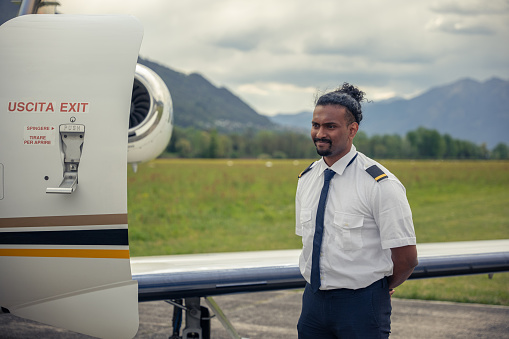 Pilot with mohawk hairstyle looks at dashboard in cockpit. Modern captain eyes scanning array of instruments with focused precision