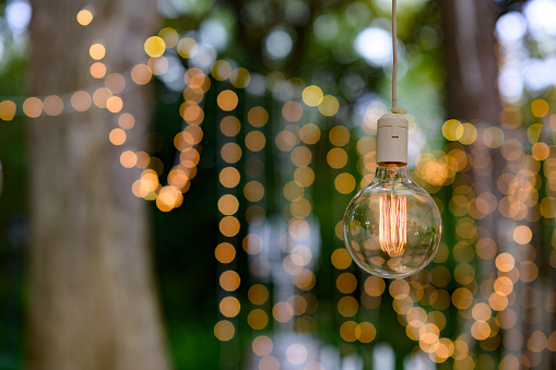 Fairy String Lights bokeh and a shing bulb hanging outdoors