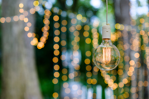 Fairy String Lights bokeh and a shing bulb hanging outdoors