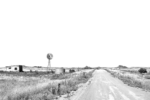 An abandoned farm worker house, windmill and dam next to road S129 between Luckhoff and Fauresmith in the Freestate Province. Monochrome