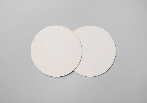 Two blank beer coasters on gray paper background. Responsive design mockup. Flat lay.