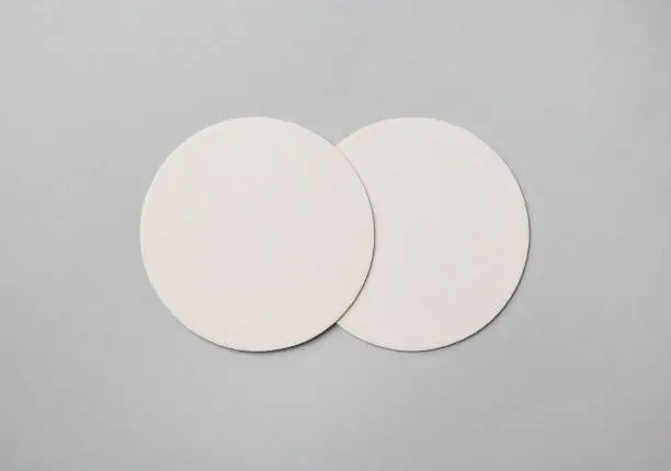 Two blank beer coasters on gray paper background. Responsive design mockup. Flat lay.