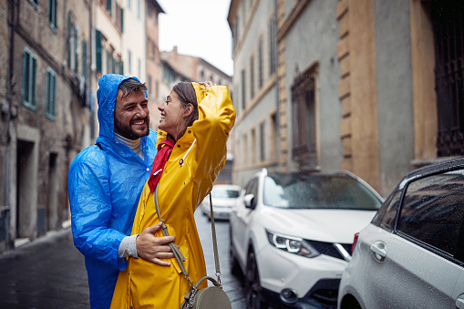 A young happy couple enjoying a rain while walking the city on a cloudy day. Walk, rain, city, relationship