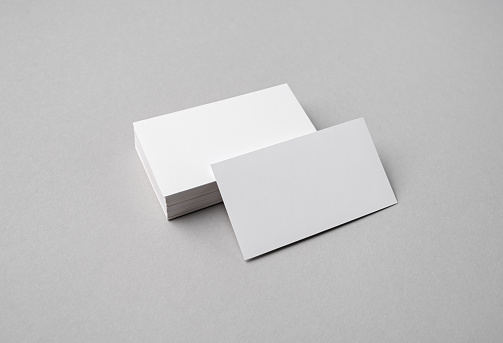 Blank white business cards on gray paper background. Mock-up for branding identity.