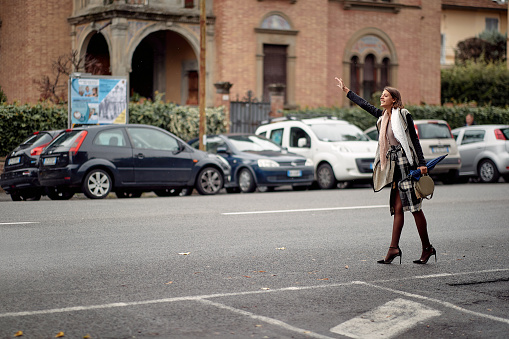 Hurried businesswoman on the street stops taxi