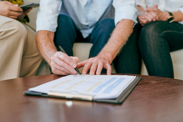 istock Close-up of man signing paperwork on table 1487719545