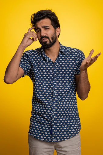 No idea, I dont know answer. Puzzled clueless uncertain indian handsome man raising hands in helpless gesture, embarrassed confused by difficult question. Confused one guy on yellow studio background