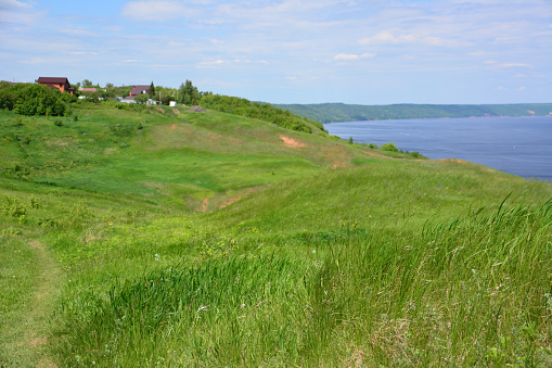 A grassy field with a view of the lake and the village on the hill in the background