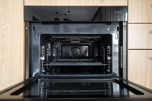 Close up view of empty and clean oven built in kitchen furniture. Front view of modern powerful electric bake cooker with fan and automatic cleaning function