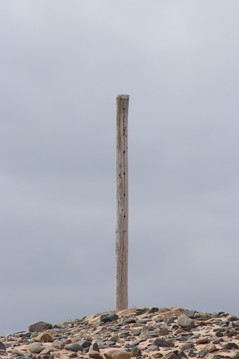 Wooden pole on pebble-covered dune